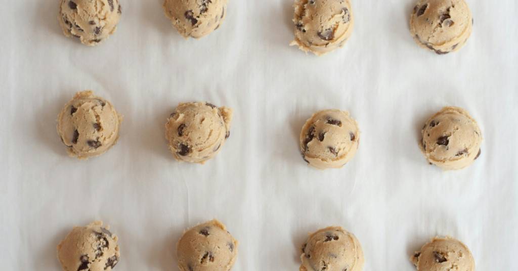 chocolate chip cookie dough scooped out and laying on a baking sheet.